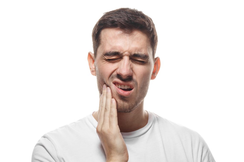 man holding his jaw in pain, indicating a severe tooth ache and possible need for root canal therapy