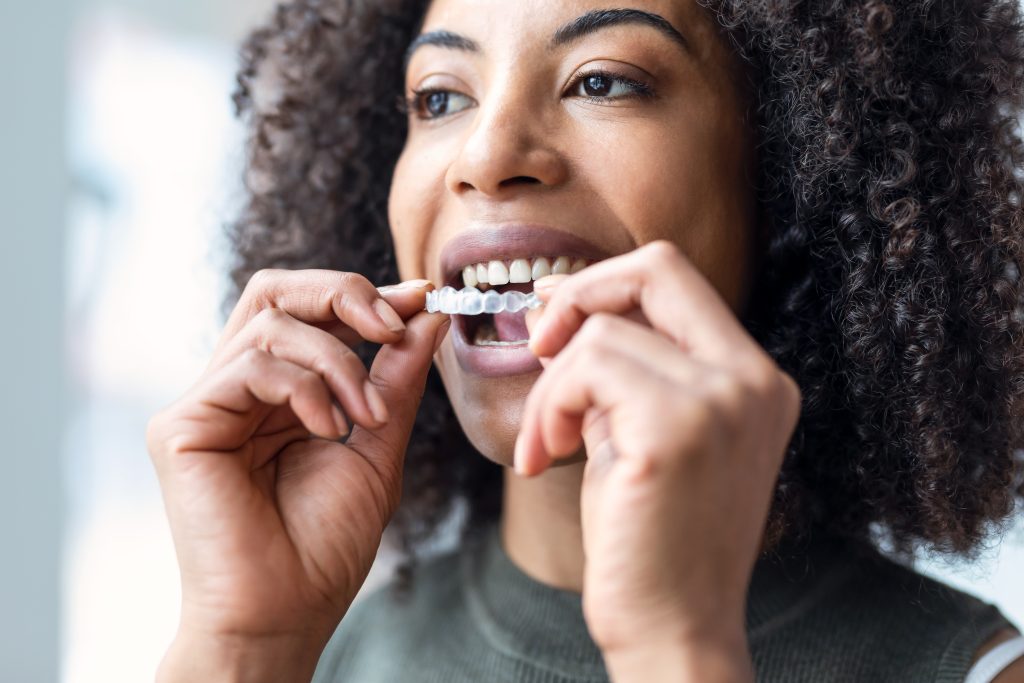 young women putting in her clear braces, Invisalign therapy